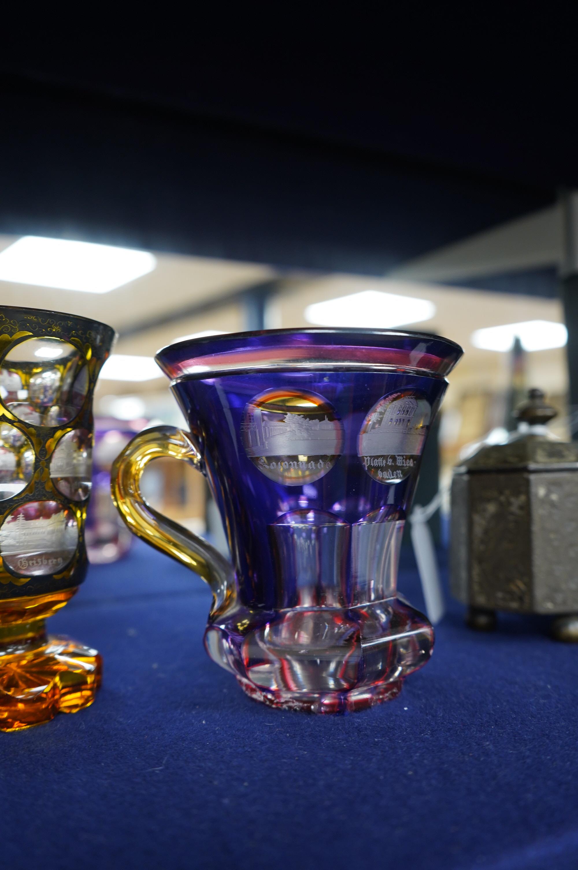 A 19th century Bohemian overlaid glass vase engraved with topographical views and a similar cup. Condition - good.